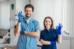 photo smiling dentist standing with arms crossed with her colleague showing okay sign